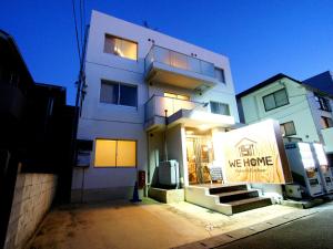 um edifício branco com um sinal que diz que nos movemos em WE HOME HOTEL and KITCHEN 市川 船橋 em Ichikawa