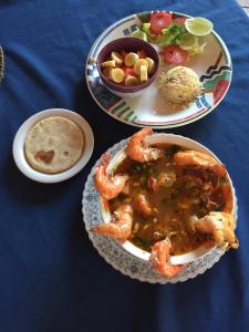 a table with three plates of food and a plate of shrimp at Casa Garrobo in Los Cóbanos
