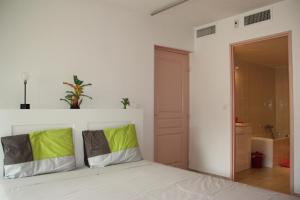 ein weißes Zimmer mit einem Bett mit grünen und grauen Kissen in der Unterkunft Appartement Ste Maxime proximité bord de mer in Sainte-Maxime