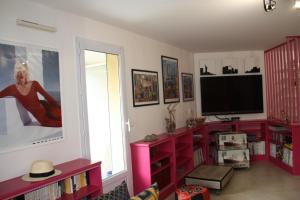 ein Wohnzimmer mit Fernseher und rotem Entertainment-Center in der Unterkunft Appartement Ste Maxime proximité bord de mer in Sainte-Maxime