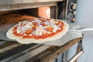 Eine Pizza kommt aus dem Ofen in der Unterkunft The Clachan Inn in Drymen