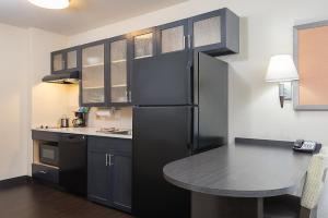 a kitchen with a black refrigerator and a table at Candlewood Suites Bloomington, an IHG Hotel in Bloomington