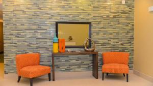 two orange chairs and a vanity with a mirror at Holiday Inn Express Hotels & Suites Cuero, an IHG Hotel in Cuero