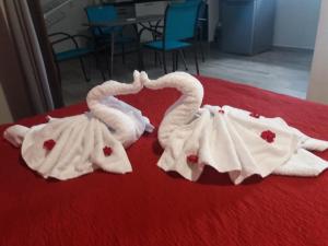two swans dressed in white towels on a bed at Locakaz in Sainte-Anne