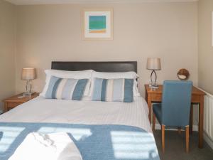 a bedroom with a bed and a desk and a chair at Guillemot in Holywell Bay