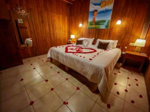 a bedroom with a bed with red flowers on it at El Jardín Hotel & Restaurante in Puyo
