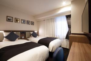 a hotel room with two beds and a window at HOTEL MYSTAYS Sapporo Susukino in Sapporo