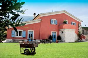 uma casa vermelha com um carrinho à frente. em La Masseria di Villa Giulia em Tocco da Casauria