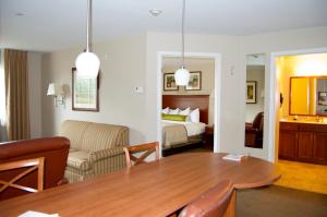 a living room with a table and a bedroom at Candlewood Victoria by IHG in Victoria