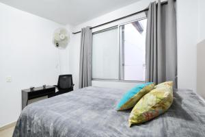 
a bed with a white blanket and pillows on top of it at International House Co-Living in Medellín

