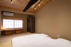 een slaapkamer met een wit bed en een raam bij 至誠宿 SHISEI-JUKU Omiya-Gojo in Kyoto