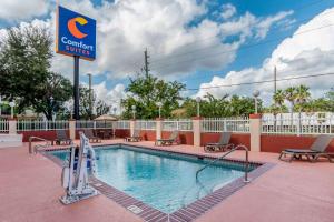a pool at a resort with chairs and a sign at Comfort Suites Airport in Jacksonville