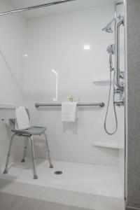a white bathroom with a chair and a shower at Holiday Inn Express & Suites - Lake Forest by IHG in Lake Forest
