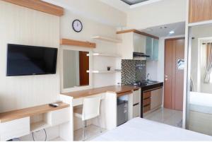 a kitchen with a desk and a tv on a wall at Sartika Apartment Margonda Residence 2 in Parungmalela +8 photos