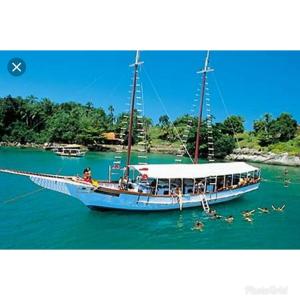 a boat in the water with people on it at Residencial Villa Nova SUITE in Boicucanga