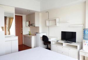 Dieses weiße Zimmer verfügt über ein Bett und einen Schreibtisch mit einem TV. in der Unterkunft Sartika Apartment Margonda Residence 2 in Parungmalela