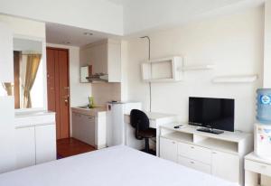 a white room with a bed and a desk with a television at Sartika Apartment Margonda Residence 2 in Parungmalela