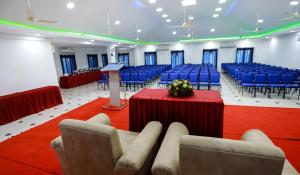 a conference room with blue chairs and a podium with a lectern at Hotel Emperor in Kannur