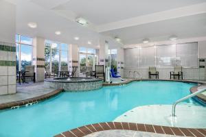a pool in a hotel with tables and chairs at Holiday Inn & Suites College Station-Aggieland by IHG in College Station