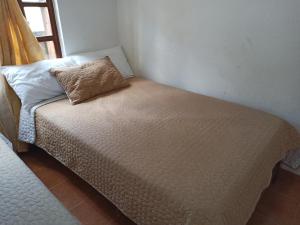 Cama pequeña en habitación con almohada en ALMANIK en Villa de Leyva
