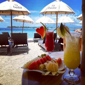 una mesa con dos cócteles y un plato de comida en la playa en La Bella - Hotel Villa & Spa, en Gili Trawangan