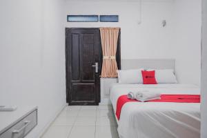 ブンクルにあるRedDoorz near Jalan Soeprapto Bengkuluのベッド2台、ドア、窓が備わる客室です。