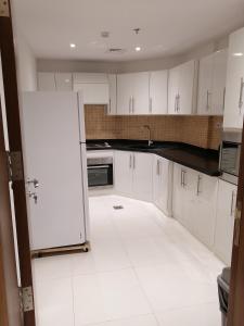 a kitchen with white cabinets and a white tile floor at Manazel Al Diafa Serviced Apartments in Riyadh
