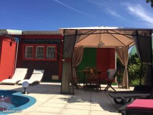 un patio con sombrilla junto a la piscina en VyvyRUN974, en Les Cocos
