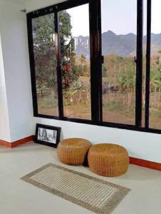 une chambre avec deux tabourets en osier devant une fenêtre dans l'établissement Adama Farmhouse @ Hacienda San Benito, à San Celestino