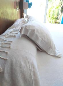 Cama blanca con almohada y ventana en Matira house en Bora Bora