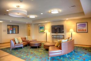 una sala de espera con sofás y sillas y TV de pantalla plana. en Candlewood Suites Alexandria, an IHG Hotel, en Alexandria
