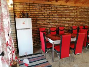 a table with red chairs and a white refrigerator at Къща за гости Морски Изгрев in Shabla