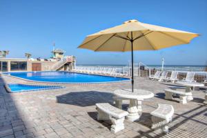una mesa con sombrilla junto a la piscina en Pirates Cove Condo Unit #704 en Daytona Beach Shores