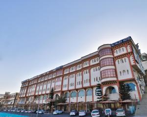 a large building with cars parked in front of it at فندق الفالح للوحدات الفندقيه in Al Baha