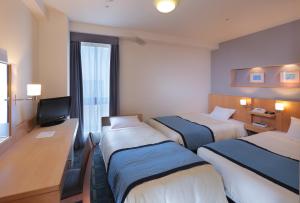 a hotel room with three beds and a television at Urawa Washington Hotel in Saitama