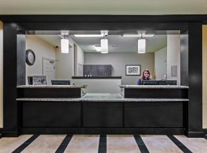 a woman is sitting at a counter in a lobby at Candlewood Amarillo-Western Crossing, an IHG Hotel in Amarillo