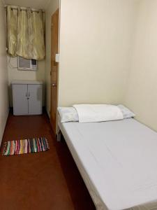 a small bedroom with a white bed and a rug at Mybed Dormitory in Cebu City