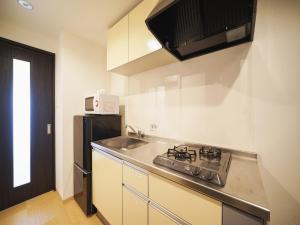 una cucina con un lavello e un frigorifero nero di BiBi Hotel Cosmos Shintoshin a Naha
