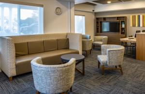 a waiting room with a couch and chairs and a table at Holiday Inn Express Hotel & Suites Roseville - Galleria Area, an IHG Hotel in Roseville