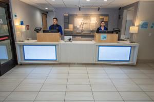 two people standing at a counter in a store at Holiday Inn Express Hotel & Suites Roseville - Galleria Area, an IHG Hotel in Roseville