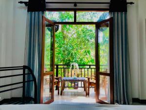 a bedroom with a door open to a balcony with a chair at Siri's Residency in Habaraduwa