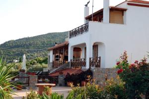 a white house with a hill in the background at Vila Elena 2 astoning view in Steni Vala Alonissos +17 photos