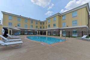 a hotel with a pool and lounge chairs in a courtyard at Holiday Inn Express Tomball, an IHG Hotel in Tomball