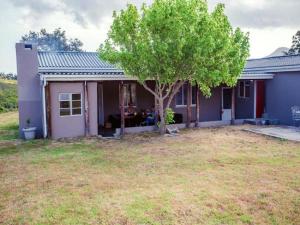 a house with a tree in front of a yard at Konings Cottage in Gansbaai