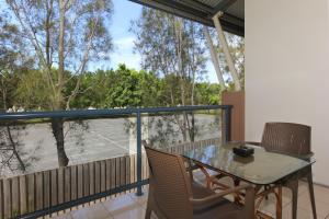 un balcón con mesa y sillas y una pista de tenis. en Novena Palms Motel en Brisbane