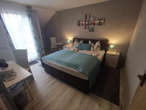Schlafzimmer mit einem Bett mit blauer Bettwäsche und einem Fenster in der Unterkunft Hennetaler Hof in Erflinghausen