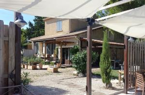 a patio with a white umbrella in front of a house at LAMATHYE in Aramon