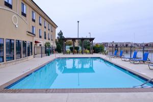 a swimming pool with blue chairs and a building at Holiday Inn Express Hotel & Suites Wichita Falls, an IHG Hotel in Wichita Falls