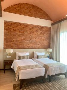 a bedroom with two beds and a brick wall at Marasa Sarovar Premiere, Bodhgaya in Bodh Gaya