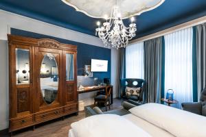a bedroom with a bed and a desk and a chandelier at Hotel Würzburger Hof **** in Würzburg